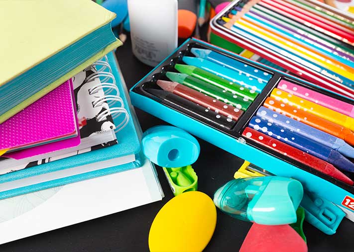 Fotografía de material escolar, ceras, cuadernos, sacapuntas y otros objetos de oficina.