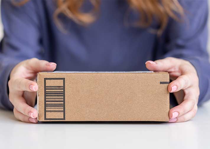 Fotografía de unas manos de mujer sujetando un paquete de paquetería.